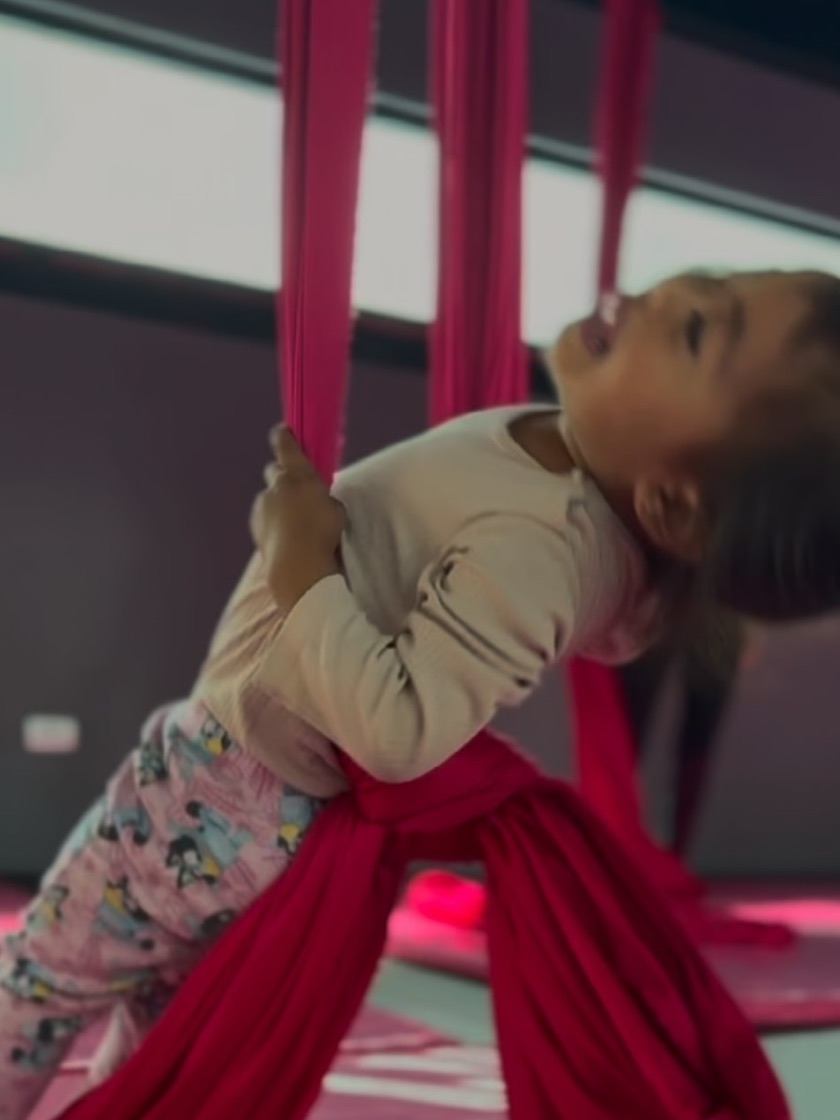 Niña pequeña jugando con las telas aéreas en clase de Baby Time.