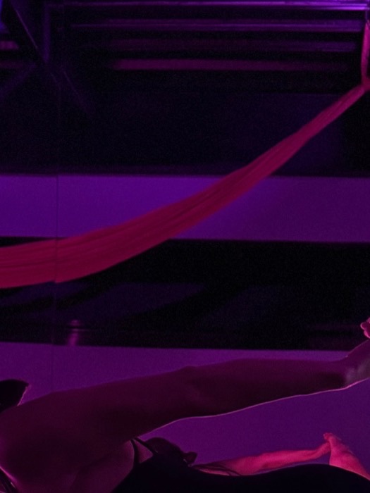 Clase de danza aérea bajo la luz rosa del estudio.